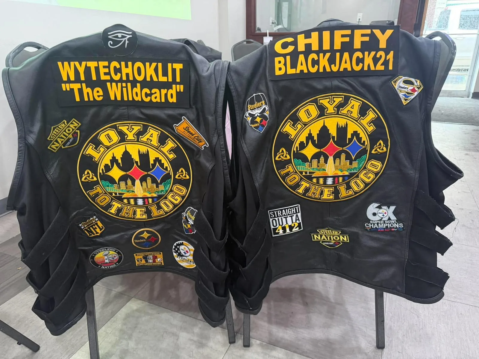 Close-up of two black vests with the embroidered round club emblem.